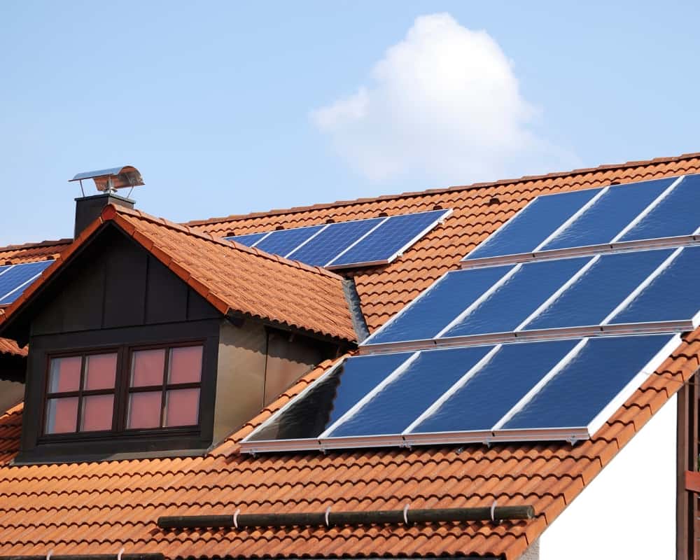 Solar panels on the roof of a home with a terra cotta roof.